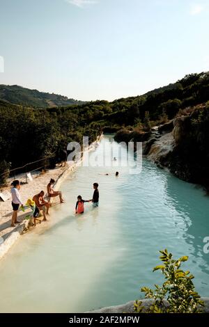 Visitatori godendo il pubblico gratuito piscina di acqua termale dell'antico villaggio termale di Bagno Vignoni, Val d'Orcia Toscana Italia EU Foto Stock