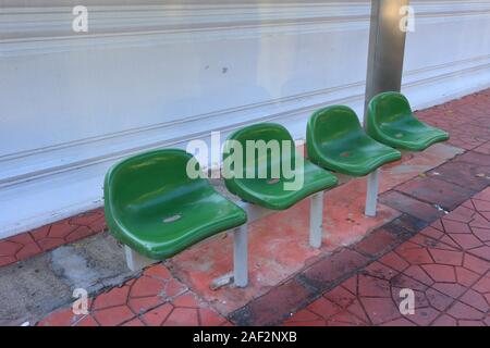 Primo piano verde vuoto sedie di plastica in corrispondenza di una fermata bus, ad alto angolo di visione Foto Stock