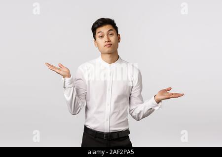 Bene dispiace ma che esso. Attraente asiatiche collega maschio non so come aiutare, scrollare e diffondere le mani lateralmente, smorfie perplesso, cant risposta, hanno Foto Stock