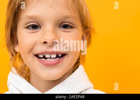 Attraente bionda sorridente ragazzo in una felpa con cappuccio bianco su uno sfondo arancione close-up Foto Stock