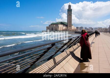 Il Marocco, Casablanca: la Moschea di Hassan II progettato dall architetto Michel Pinseau e costruito dal gruppo Bouygues dal mare. Donna sul molo facin Foto Stock