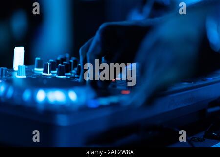 Club dj riproduce la musica sul palcoscenico in discoteca.Mano del disc jockey suono di regolazione del volume della traccia del livello.apparecchiature audio professionali su music festival Foto Stock