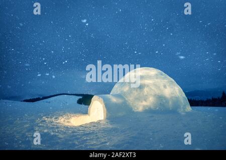 Scena invernale con snowy igloo e la via lattea nel cielo notturno. Fantastico paesaggio invernale incandescente da star light. Santa Casa da neve, ideale Anno nuovo e lo sfondo di Natale Foto Stock