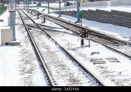 Interruttori alond coperta di neve di binari ferroviari che corre parallelo alla strada in una fredda soleggiata giornata winnter Foto Stock