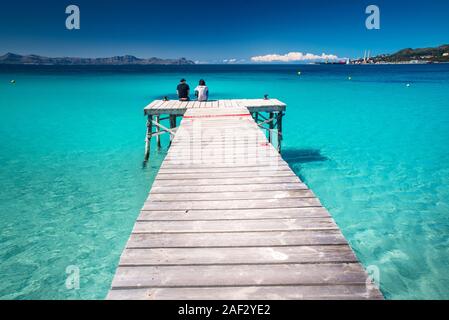 Tourist seduti insieme sul molo in mare tropicale. Spagna. Foto Stock