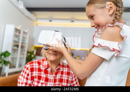 Lieta signora anziana utilizzando 3D occhiali VR Foto Stock