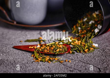 Giapponese 'Genmaicha' tè, un riso marrone tè verde costituito da tè verde miscelato con arrosti di popping riso marrone, la fuoriuscita del contenitore Foto Stock