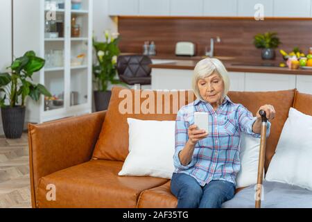 Grave donna senior guardando il suo smartphone Foto Stock