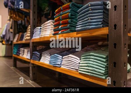 I vestiti sono impilate ordinatamente sugli scaffali del negozio. Camicie, jeans Foto Stock