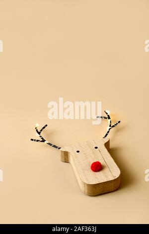 Un divertente di renne in legno di testa, con un naso rosso, su uno sfondo di colore marrone con qualche spazio vuoto sulla parte superiore Foto Stock