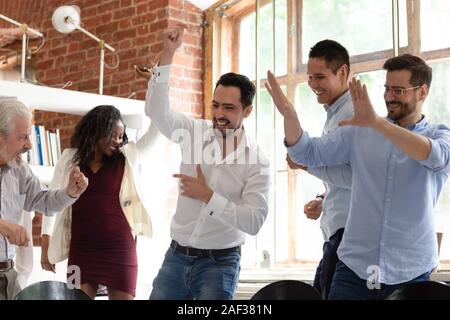 Multirazziale colleghi dancing godere party aziendale o di celebrare la trattativa di successo Foto Stock