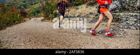 Donna e uomo corridori eseguire il sentiero di montagna in autunno le nuvole Foto Stock