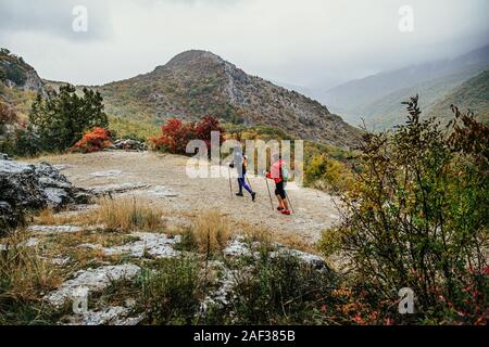 Due escursionisti camminatori con pali trekking andare in mountain trail in autunno piovoso meteo Foto Stock