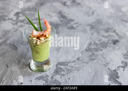 Avocado e mela verde mousse con gamberi e mandorle. Porzione antipasto per un buffet o un banchetto in un bicchiere. Foto Stock