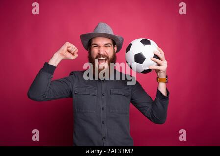 Foto di stupito uomo con pallone da calcio e celebrare il successo Foto Stock