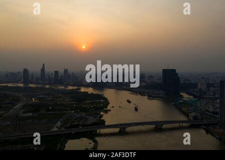 Il fiume Saigon tramonto con estrema dell'inquinamento atmosferico. Bel colore arancione, red sky e riflessioni con la città di Ho Chi Minh, Vietnam Skyline. Foto Stock