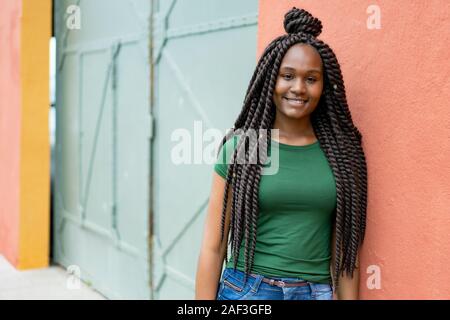 Bella americano africano giovane donna adulta con fantastica pettinatura all'aperto in estate in città Foto Stock