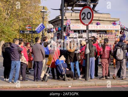 Tour guida alzando il gruppo assegnato numero di flag (L01-5) con i turisti si riuniscono intorno a Westminster Londra Foto Stock