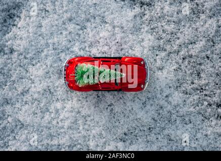 Vista cielo di uno scarabeo auto con un albero di Natale sulla sommità parcheggiato nella neve Foto Stock