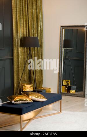 Bellissimo e nuovo anno il decor in studio. Oro tessuto a trama sullo sfondo, lampada, specchio di grandi dimensioni, blu poof, regali 2020 Foto Stock