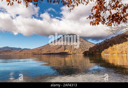 Il Lago Chuzenji (Nikko, Giappone) con montagne che si riflettono nell'acqua in una giornata di sole a fine ottobre. Foto Stock