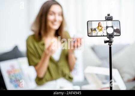 Giovane donna registrazione del suo vlog circa una sana alimentazione e supplementi nutrizionali, close-up su una schermata telefono. Medicina Preventiva e influencer marketing concept Foto Stock