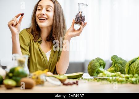 Ritratto di una giovane donna allegra con secchi di rosa canina e un sacco di sano cibo verde sul tavolo. Concetto di vegetarianismo e benessere Foto Stock