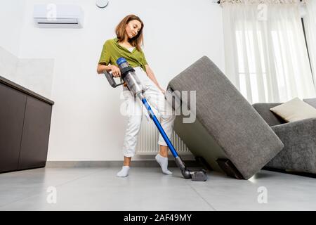 Giovane donna di pulizia con divano cordless di aspirapolvere in bianco  moderno salotto. Concetto di facilità di pulizia con un wireless  aspirapolvere Foto stock - Alamy