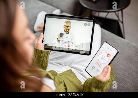 Donna che fa il video a una chiamata a un medico utilizzando digitale compressa, sensazione di cattivo a casa. Concetto di telemedicina e paziente counseling online Foto Stock