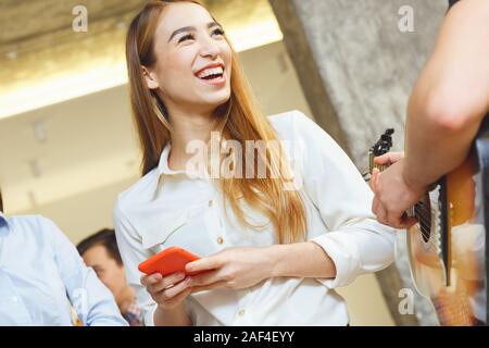 Gruppo di amici aventi parti in ambienti chiusi insieme divertimento donna smartphone holding close-up Foto Stock