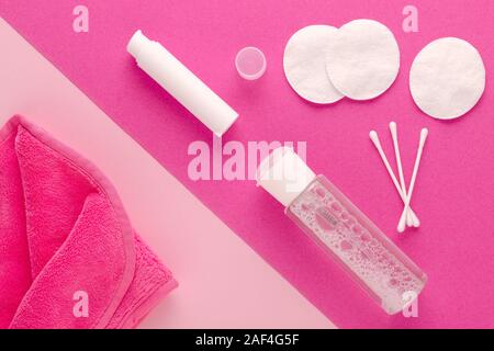 Make up rimuovere prodotti, acqua micellare faccia, panno per pulizia, latte detergente e batuffoli di cotone su sfondo rosa Foto Stock