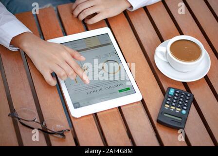 Primo piano di tablet digitali nelle mani delle donne con un concetto di funzionamento delle tazze da caffè Foto Stock