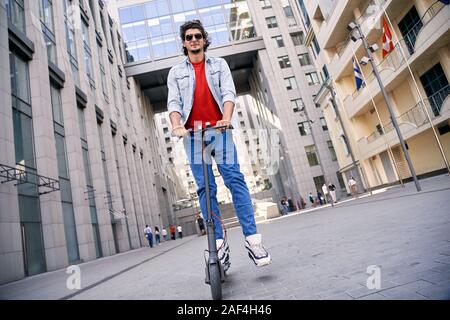 Giovane uomo adulto ride su scooter elettrico Foto Stock