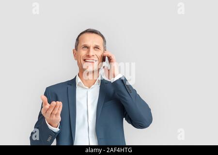 Freestyle. Imprenditore maturo in piedi isolato su bianco parlando sullo smartphone felice Foto Stock