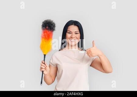 Freestyle. Donna asiatica in piedi isolato su bianco con duster mostra pollice in alto positivo Foto Stock
