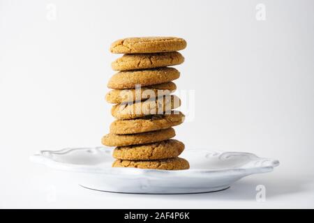 Una pila di biscotti allo zenzero su una piastra bianca isolata su uno sfondo bianco con spazio copia; paesaggio Foto Stock