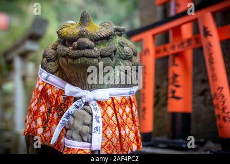 Kyoto, Giappone - 24 Marzo 2017 : vestito dio statua e cancelli dei tori a Fushimi Inari Shrine, presa in un assolato pomeriggio di primavera Foto Stock
