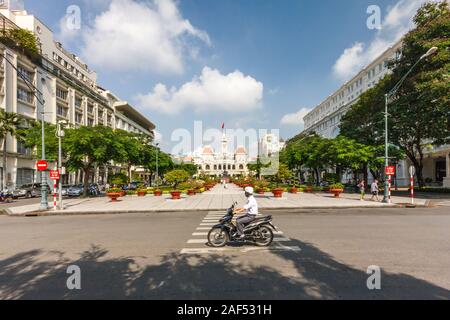 La città di Ho Chi Minh, Vietnam - 30 Ottobre 2013: un motociclista sposta lungo la strada. In fondo è il comitato di popoli edificio. Foto Stock