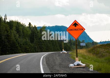 Condizione temporanea segnaletica stradale, lavori di costruzione. canadese sulla paese rurale strada con alberi di pino foreste sfondo, avvertenza simbolo arancione Foto Stock