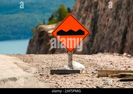 Piazzola o pavimentazione irregolare sulla strada segno arancione sulla massa nel fuoco selettivo vista, condizione temporanea segnaletica stradale Foto Stock