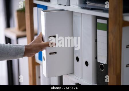 Commercianti la mano tenendo cartella dal ripiano di legno in Office Foto Stock