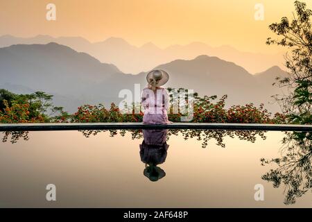 Pu Luong comune, Thanh Hoa provincia, Vietnam - Ottobre 1, 2019: donna asiatica nel vestire in piedi sulla piscina infinity edge e natura scena. Reso di lusso Foto Stock