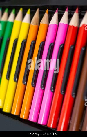 Set di legno luminoso matite colorati disposti in una fila con uno sfondo scuro. Articoli di cancelleria lo sfondo con un'arte e concetto di istruzione. Foto Stock