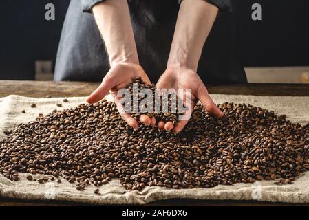 Mani fragranti caffè in grani su uno sfondo scuro. Un mucchio di arrosto chicchi di Arabica. Selezione di caffè per espresso Foto Stock