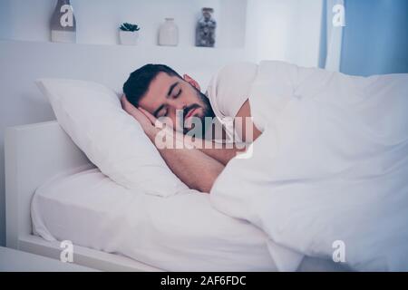 Close-up ritratto della sua egli bella tranquilla attraente brunette ragazzo disteso sul letto bianco in appoggio addormentati tempo di sonno durante la notte tarda sera home Foto Stock