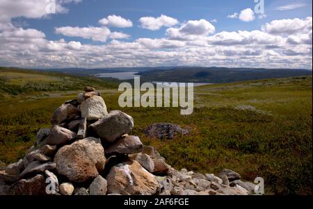 Un uomo fatto cairn mucchio di pietre di roccia a Skogshorn in montagna Hemsedal Norvegia con un suggestivo scenario areale in un giorno nuvoloso Foto Stock