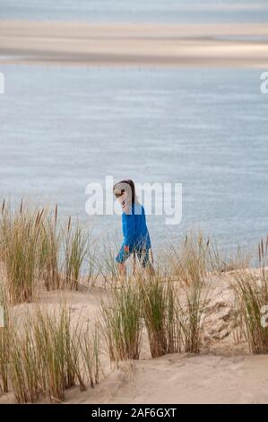 Giovane ragazza che indossa un vestito blu a piedi sulla duna del Pyla con vista al mare, baia di Arcachon, Gironde (33), Nouvelle-Aquitaine, Francia. Foto Stock