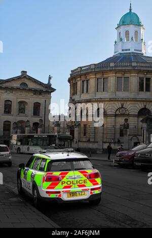 Auto della Polizia su Broad Street, Oxford, Inghilterra, con lo Sheldonian Theatre e la Libreria di Bodleian Clarendon Building, Università di Oxford, in background. Foto Stock