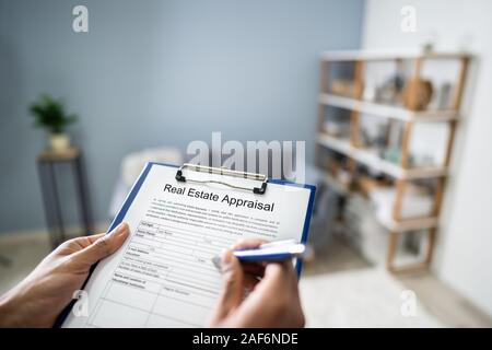 Close-up di mano di una persona il riempimento di valutazione immobiliare forma con penna Foto Stock