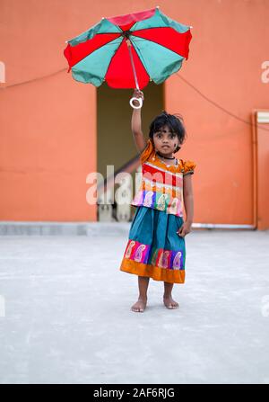 Il bambino tiene un grande ombrello coloratissimo sopra la sua testa, Foto Stock